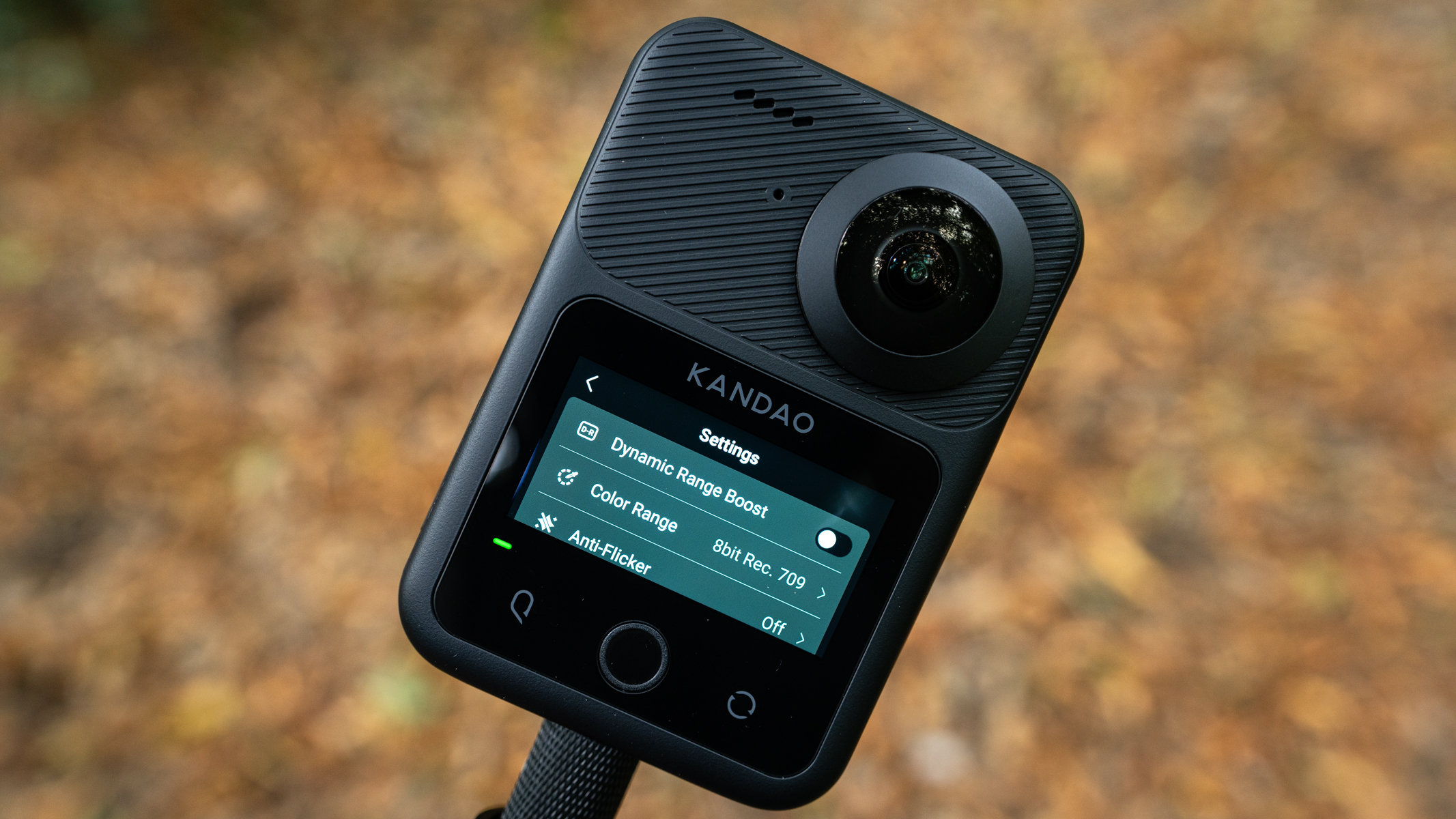 Kandao QooCam 3 Ultra action camera outside in front of brown leafy ground