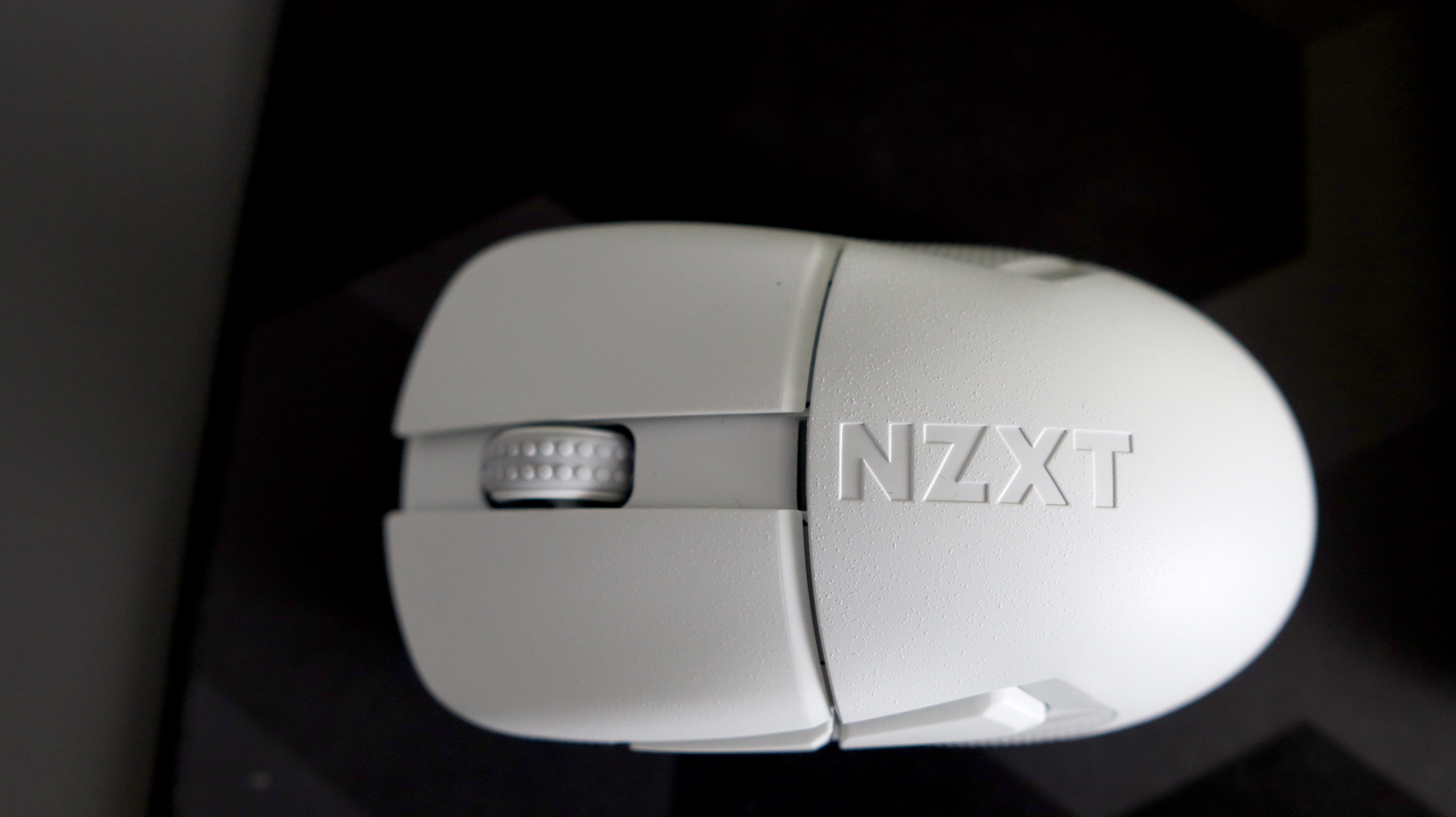 An NZXT Lift Elite Wireless gaming mouse in white set-up on a desk.