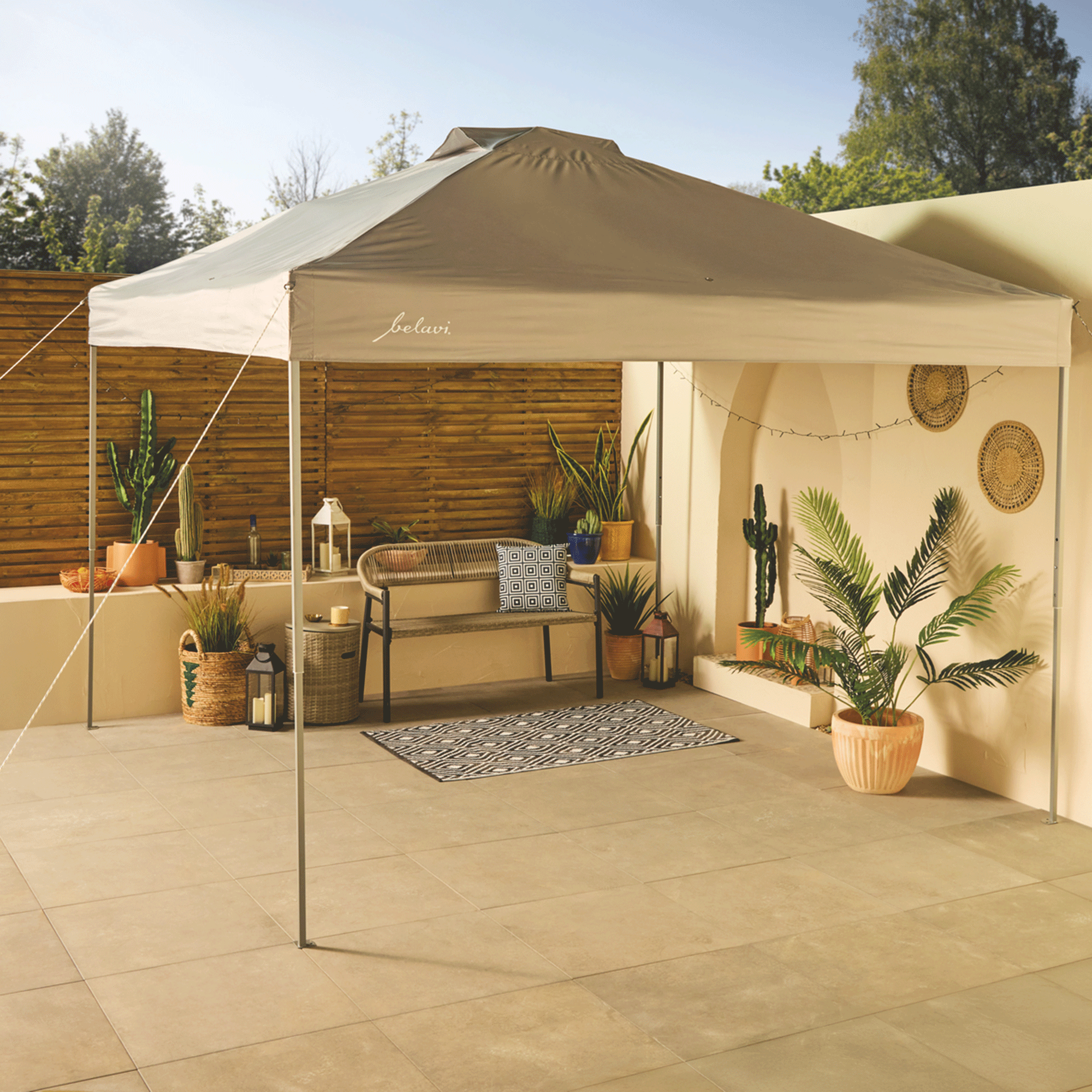 Aldi canopy set up over a patio garden with terracotta pots, plants and a wooden fence