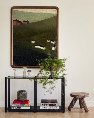 hallway console table with artwork above it, stool and plant pot