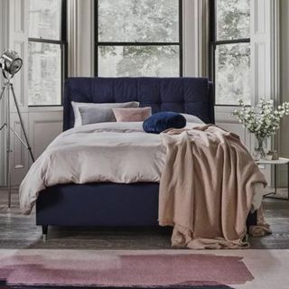 blue bed frame with white bedding on top