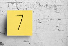the number seven on a yellow note posted on a brick wall