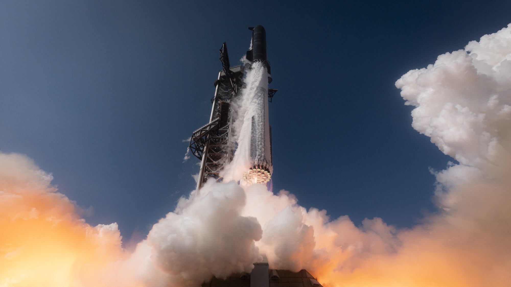 Um imponente foguete SpaceX Starship Flight 12 decola em um céu azul expelindo nuvens gêmeas de fumaça
