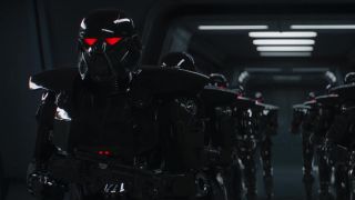 Still from The Mandalorian TV series. There are two rows of menacing super soldiers. They are wearing heavy black armor, complete with a black helmet with glowing red eyes. They each hold a large gun.