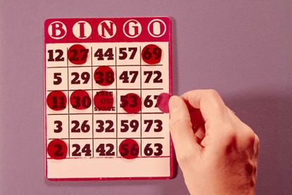 A hand marking a bingo card, illustrating the origins of Bingo