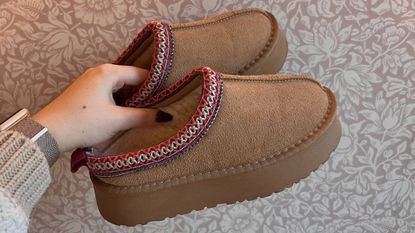 A person holding a pair of Ego Tazmin Aztecs (Ugg Tazman dupes)