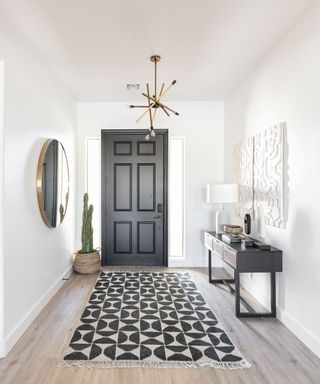 Black and white entryway with geometric runner and cactus in the corner