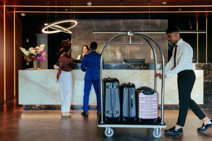 Hotel attendant with luggage in lobby.