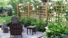 A backyard with small patio area with black garden furniture, and a trellis fence with white hydrangeas, one of the most popular fence ideas