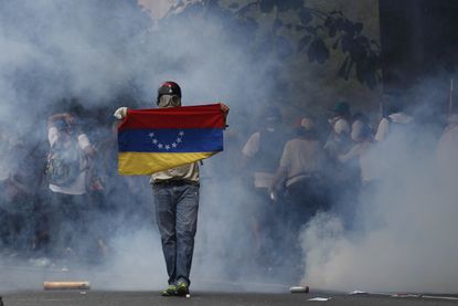 An anti-government protester holds a Venezuelan flag.