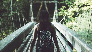 Photo of a woman walking over a scenic wooden bridge