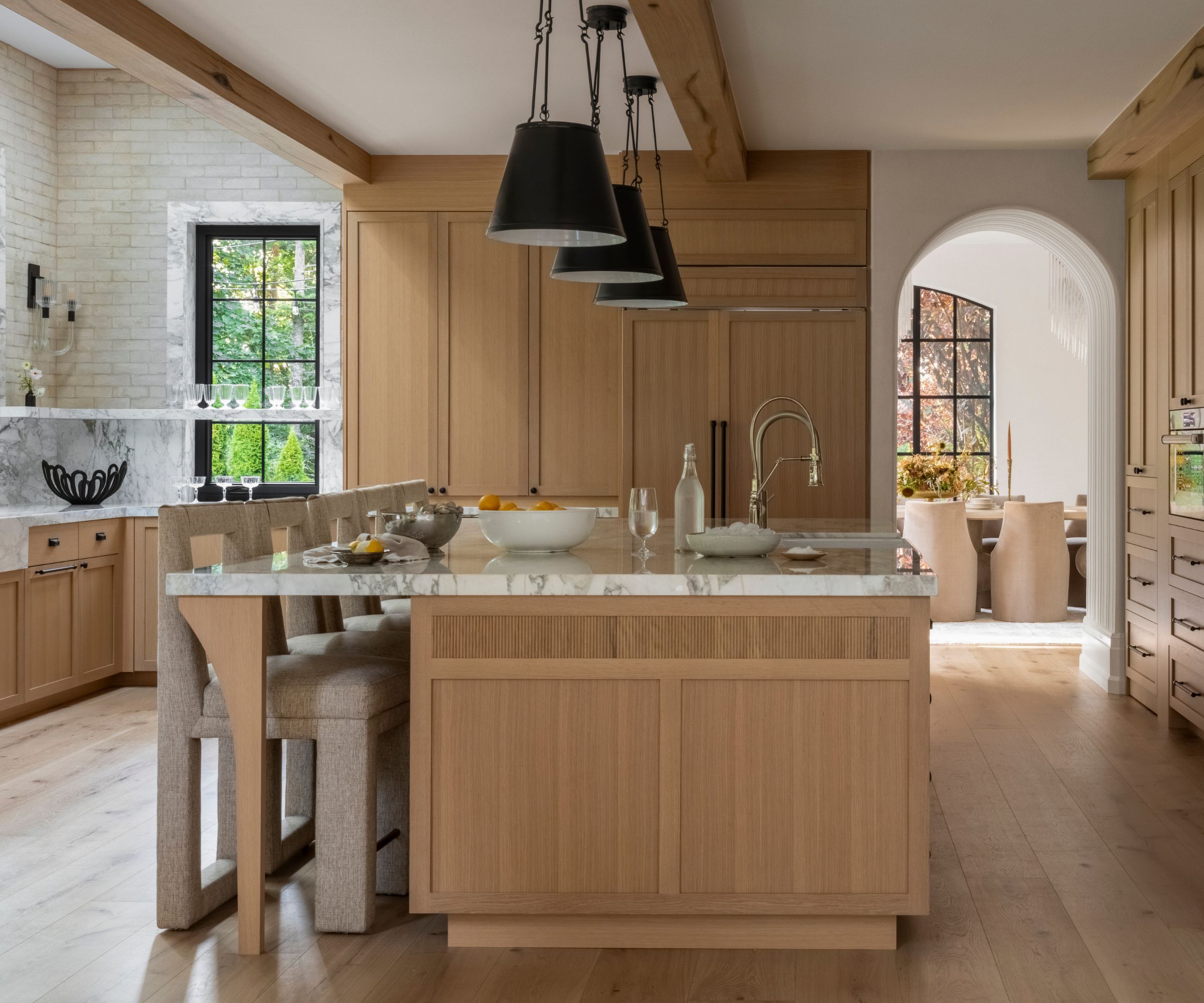 A wooden kitchen with a large island featuring storage on both sides and spacious counter seating