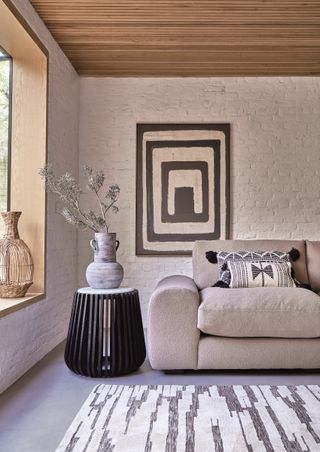 living room with wooden panelled ceiling, stone colored sofa, rug and contemporary artwork