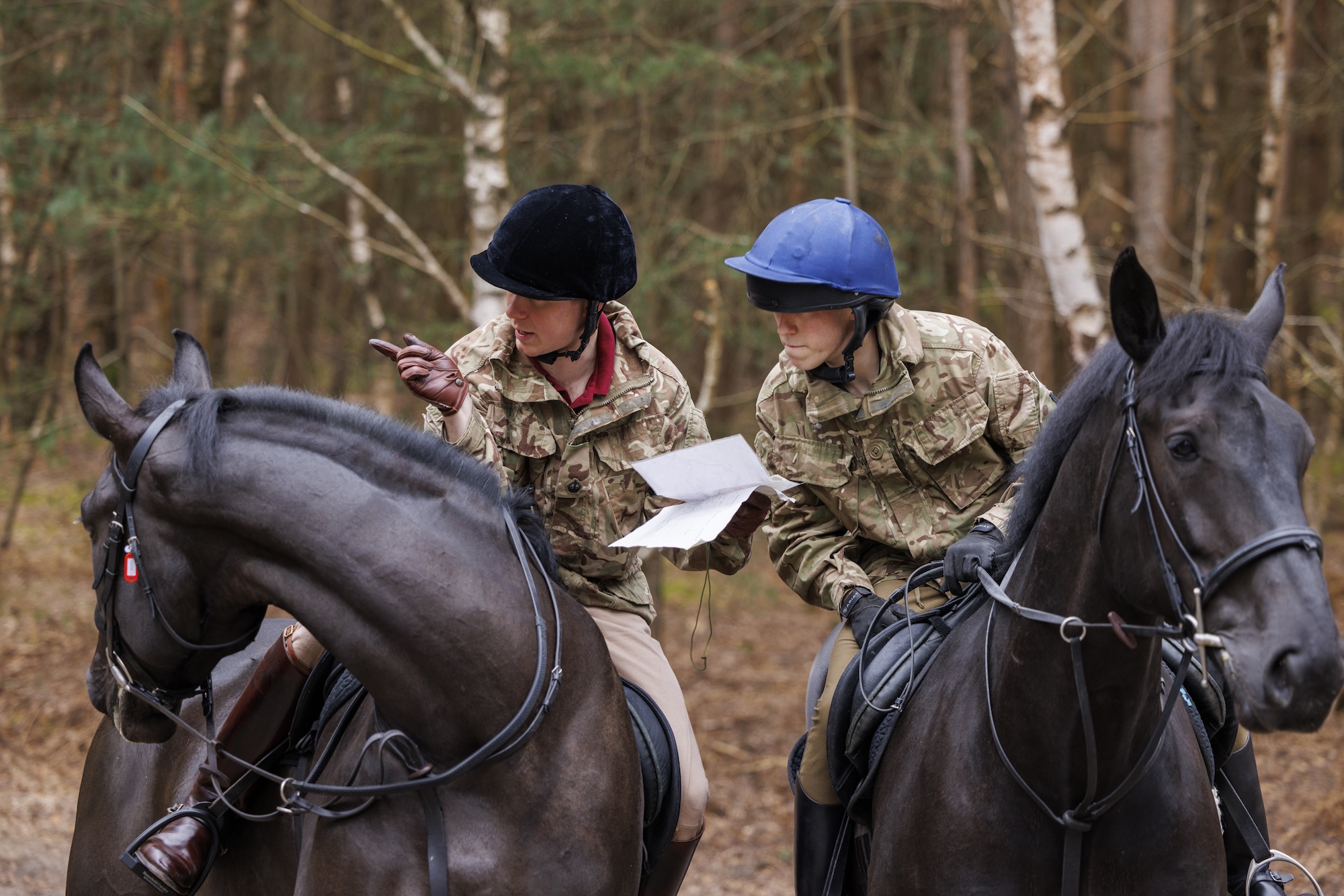Two soldiers on horses consult a map