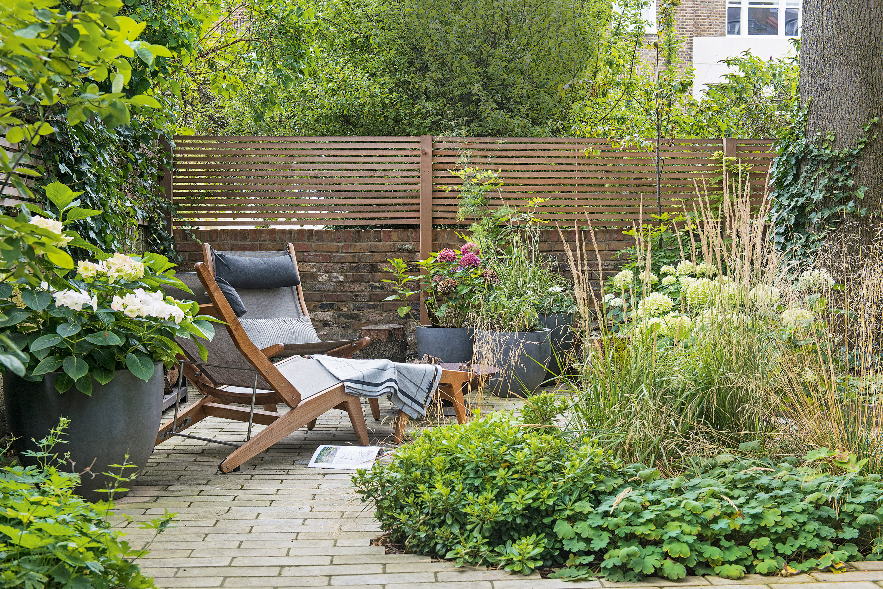 loungers on a patio and surrounded by flowerbeds