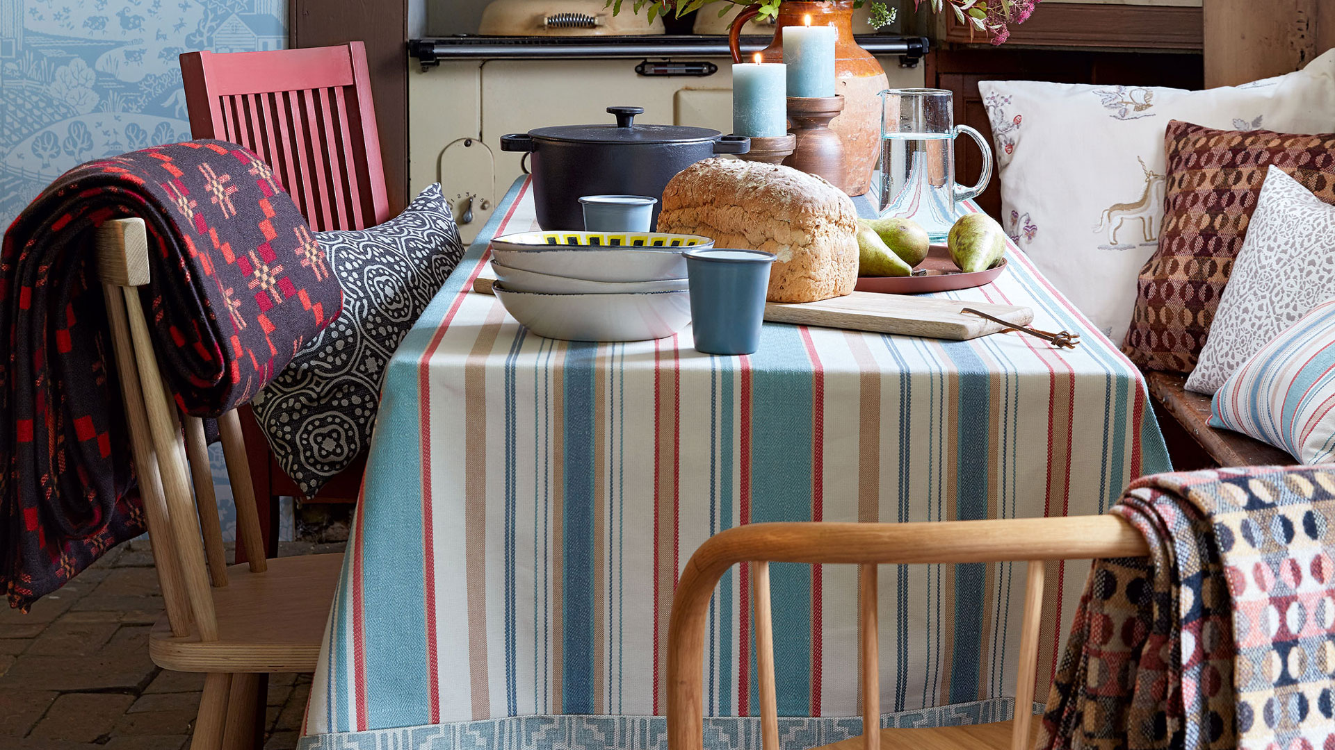 light blue kitchen with a dining table with a striped tablecloth with a loaf of bread and bowls stacked