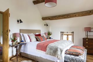 master bedroom with Welsh blanket and pink throwin restored Welsh barn