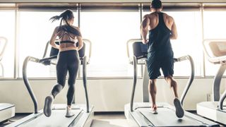 Man and woman running on flat treadmills side by side