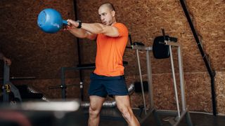 Man performs kettlebell swing in gym