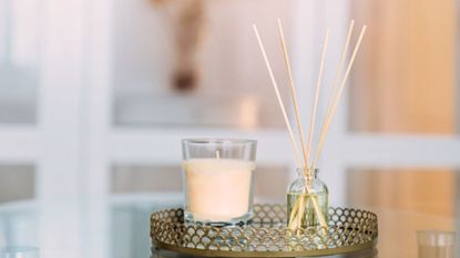 reed diffuser vs scented candle on a table with a blurred background