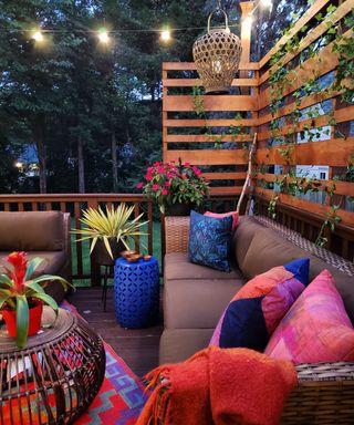A colorful deck idea using faux climbing plants, cushions and brown rattan furniture