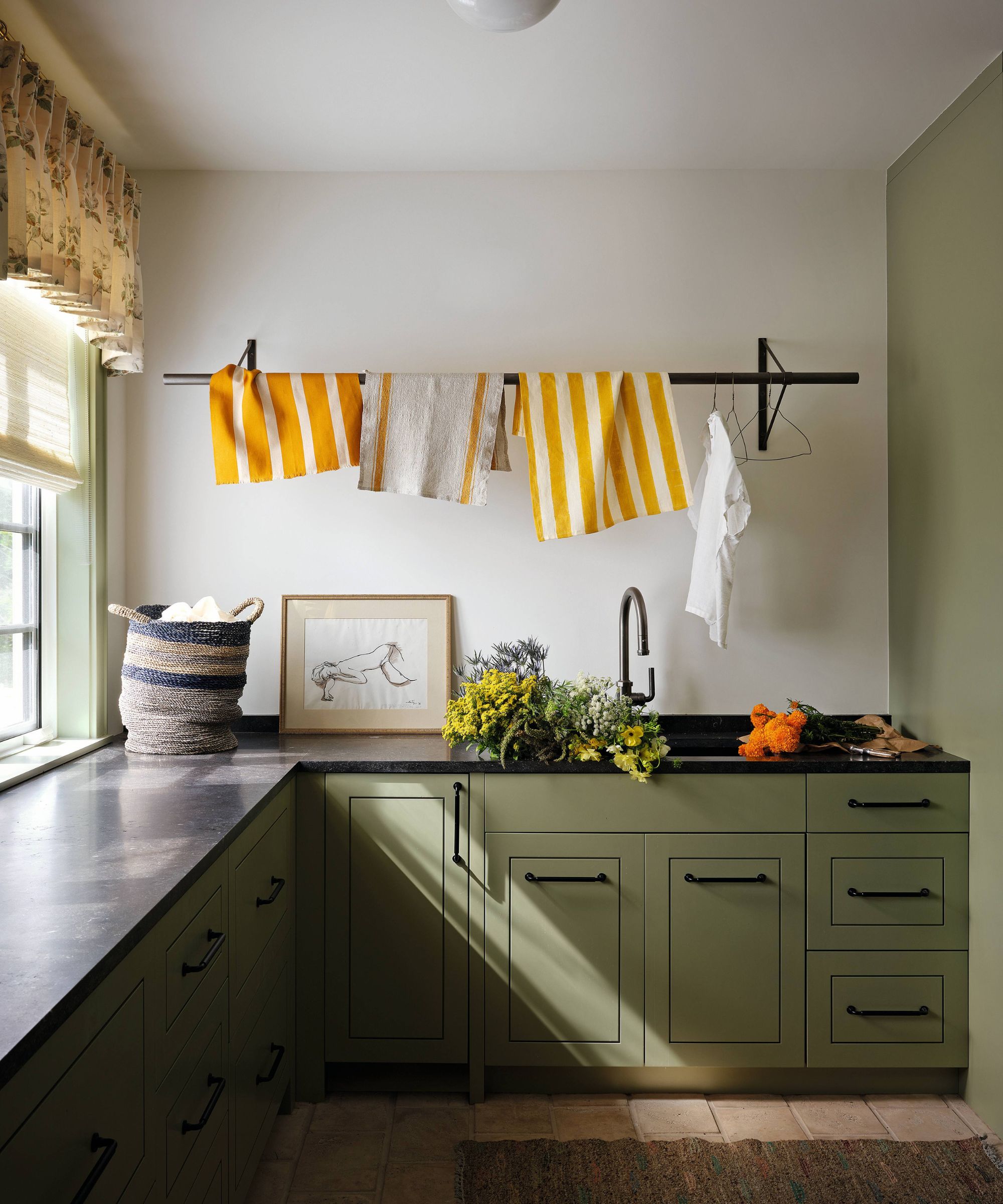 a mid green painted boot room with hanging laundry rail, a sink and dark counters and hardware