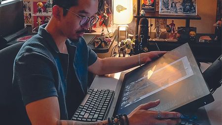 Artist in residence, Erik Ly; a man sits in front of a Wacom drawing tablet