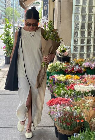 a photo of a woman's white dress outfit with long maxi styled with silver necklace, white ballet flats, and a black tote bag