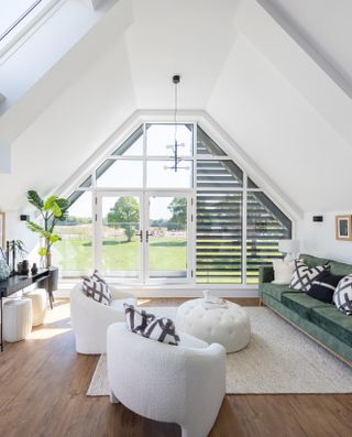 An open plan Scandinavian style living room with a vaulted ceiling and French windows onto a garden