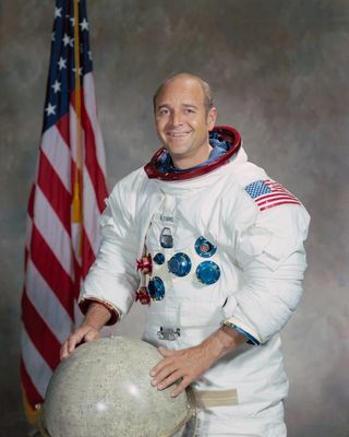 Astronaut Ronald E. Evans poses for his portrait smiling with two hands on the globe.