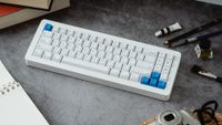 The WhiteFox Eclipse Mechanical Keyboard on a desktop with paint and pencils nearby. 