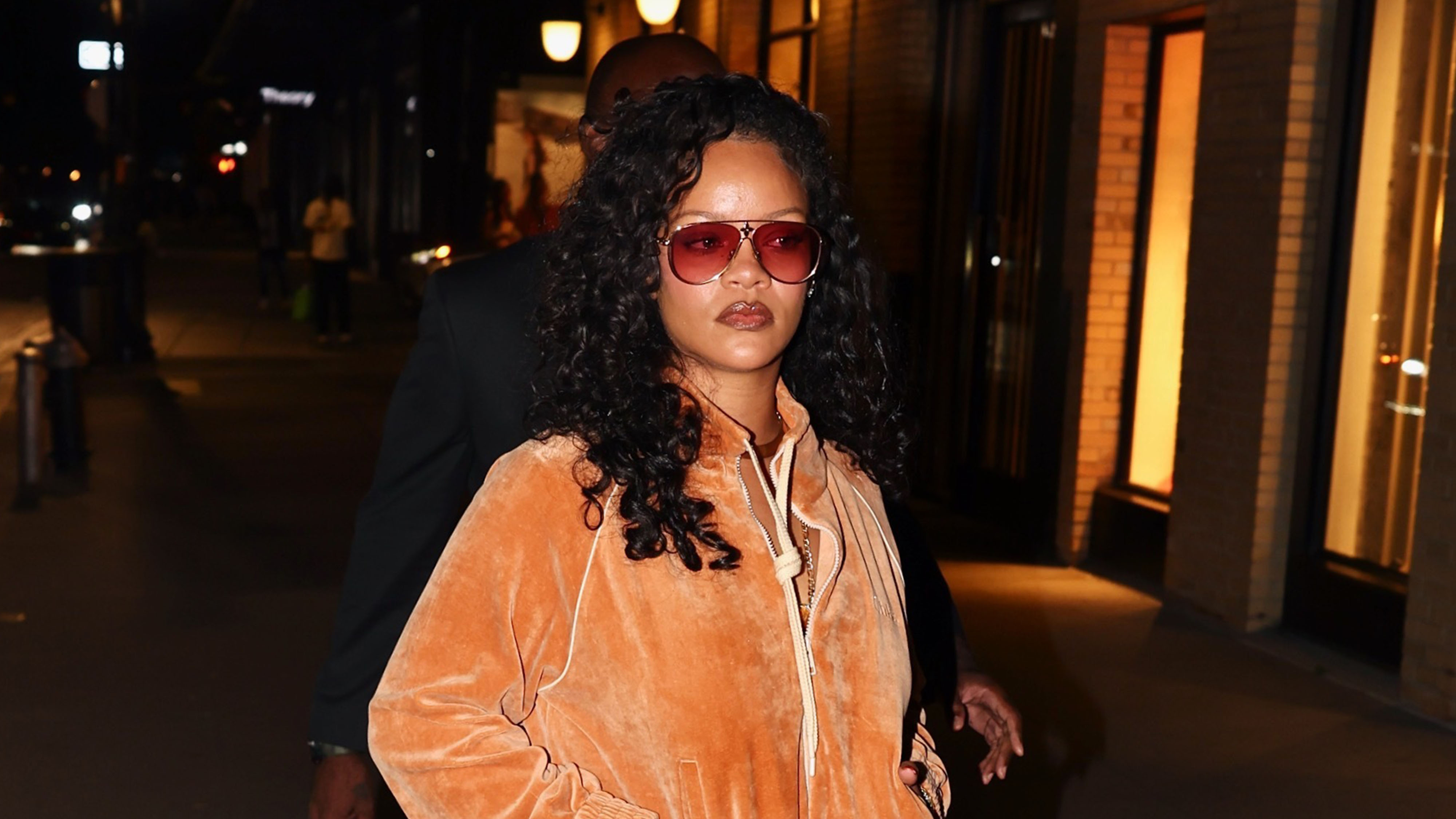 Rihanna wearing an orange sweatsuit and heels.