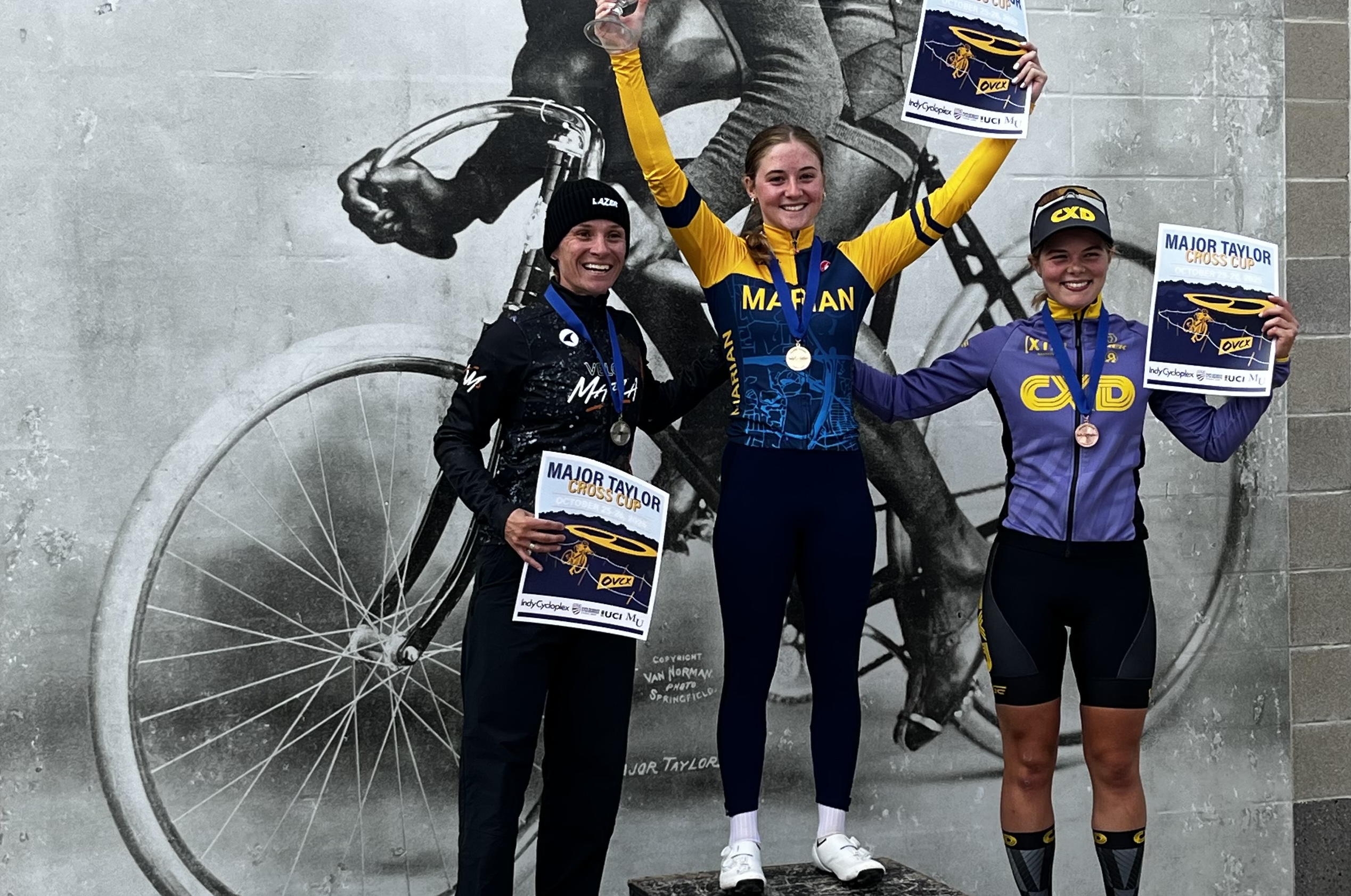 Lizzy Gunsalus stands on top step of the podium on Saturday at 2025 Major Taylor Cross Cup, with Caroline Mani in second (left) and Lyllie Sonnemann in third (right)