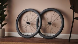 A pair of FFWD Ryot 55 road bike wheels leans against a terracotta wall