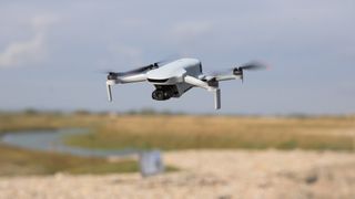 Potensic Atom 3 beginner drone in flight over a coastal landscape on a mixed cloudy / sunny day