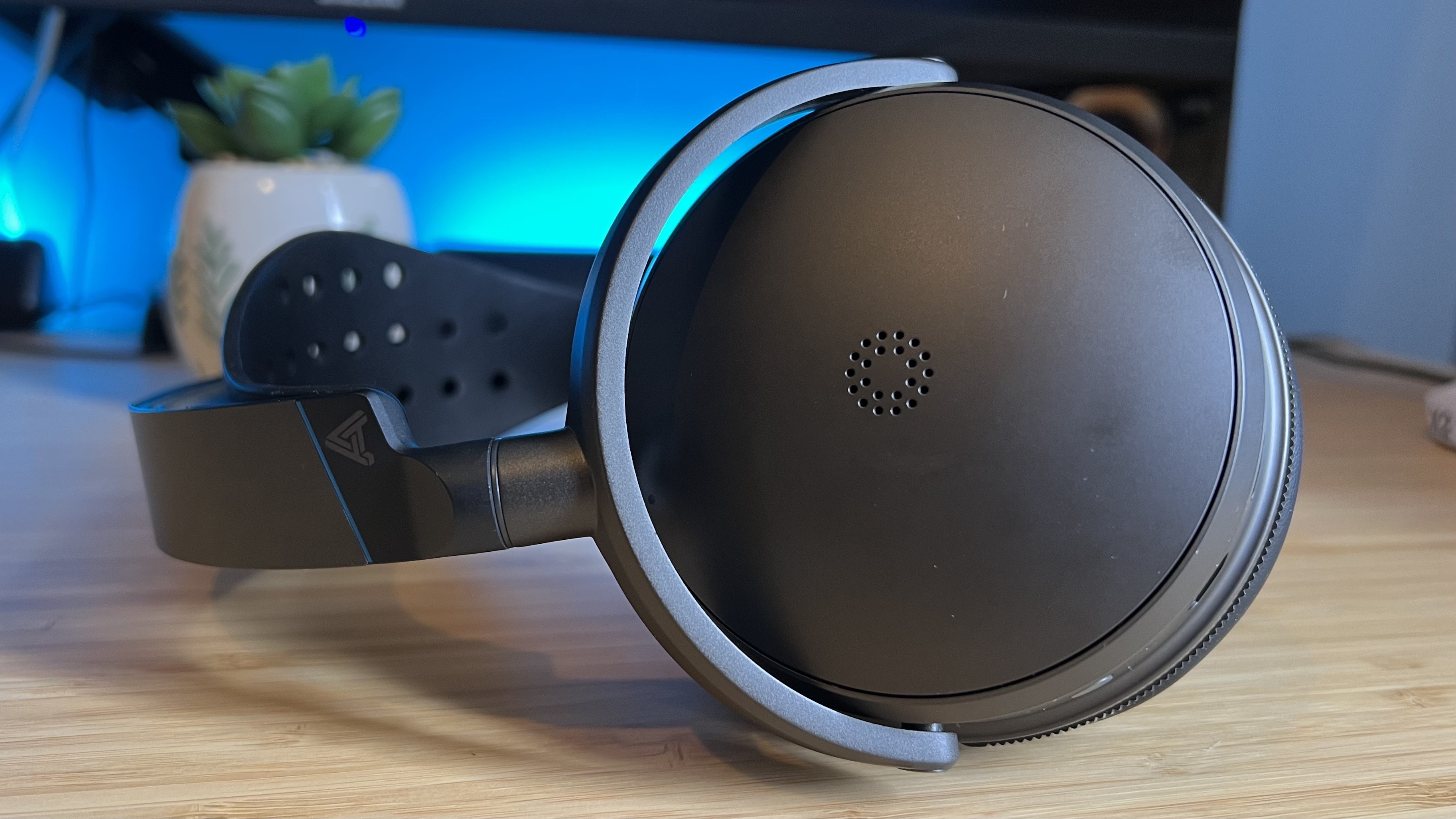 Close up on left earcup of Audeze Maxwell 2 gaming headset on a wooden desk