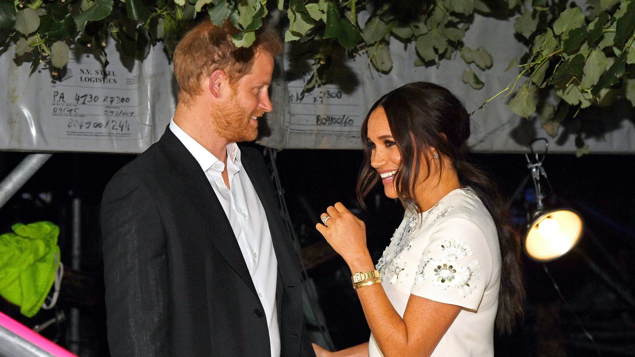 Prince Harry and Meghan Markle smile at each other under a tree