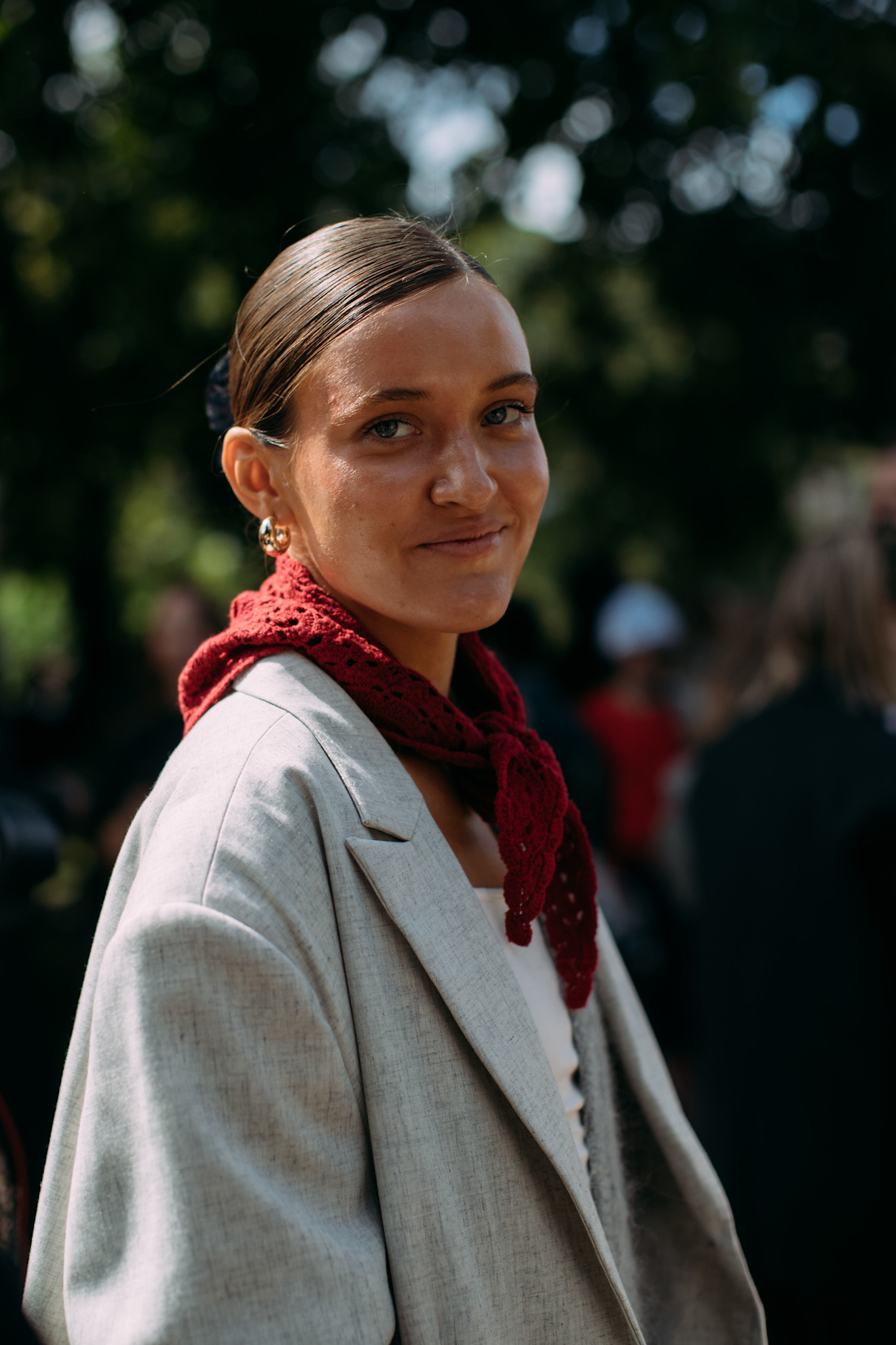 a woman at copenhagen fashion week wearing a red triangle scarf, white top, and gray blazer