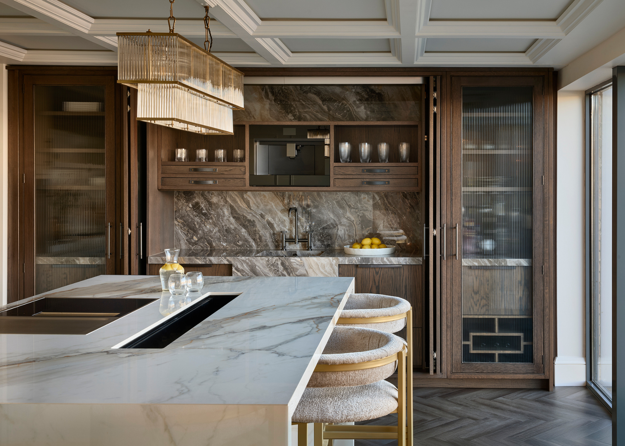 luxurious kitchen with a large porcelain island and glass reeded cabinets