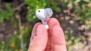 LG Tone Free T90 earbud held between reviewer's finger tips