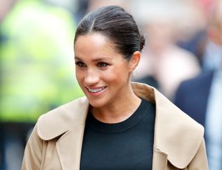 Meghan Markle wearing a camel colored coat and black dress