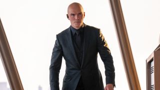Nicholas Hoult's Lex Luthor dressed in black suit standing near a large window behind him