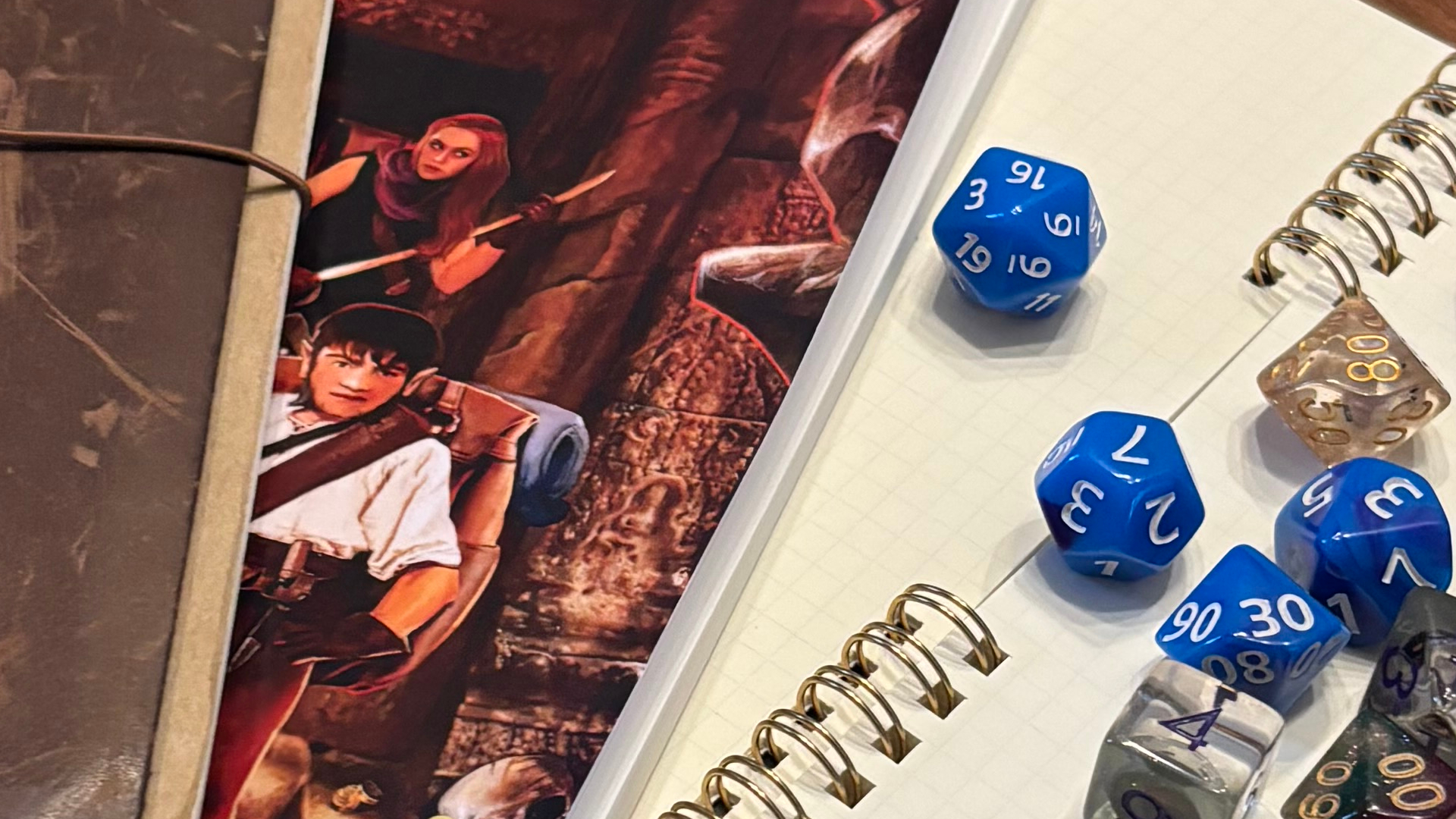 Artwork depicting adventurers between notebooks, surrounded by dice