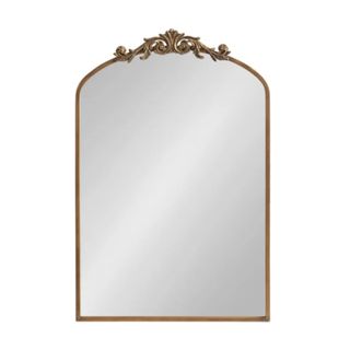 A gold mirror with ornate detailing on top