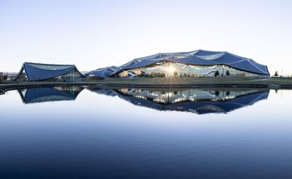 Exterior view of the Google Bay View Campus, taken from afar. The building is in the distance, and closer to the camera is a lake.