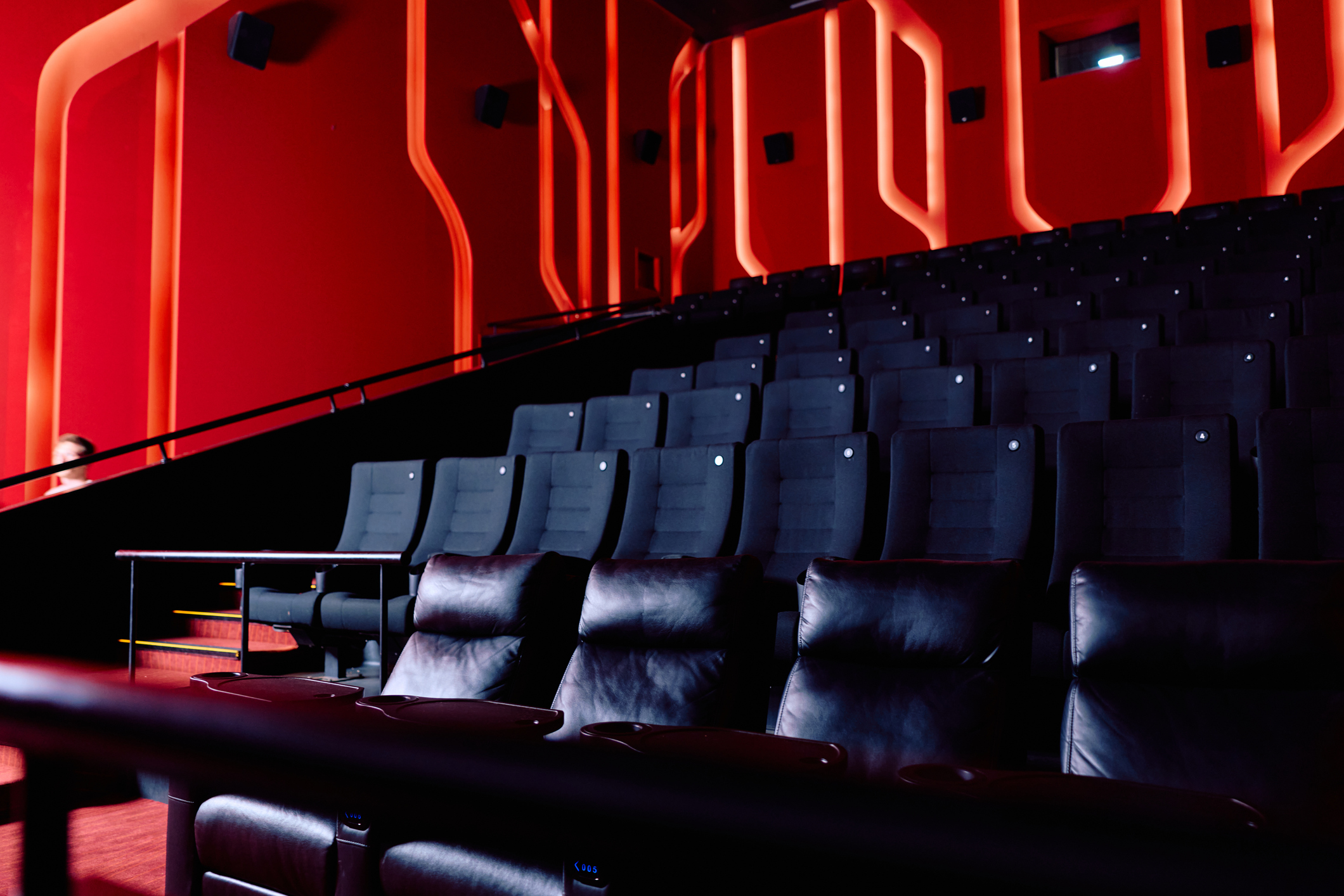 Empty modern cinema auditorium with luxury seating and red lighting