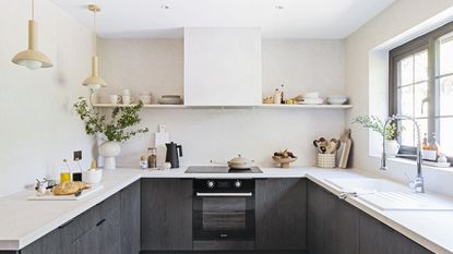 Dark grey kitchen units with belfast sink and wall panelling with peg rail shelf