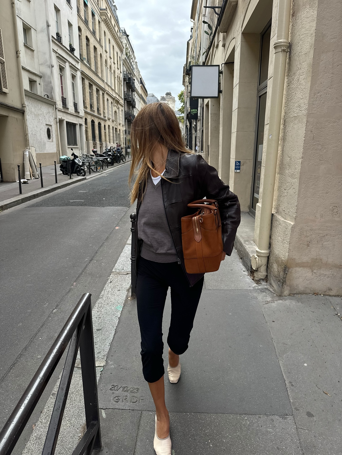 Fashion person annelauremais wears a leggings outfit 2026 . She wears black capri leggings, a grey jumper, white t-shirt and washed black leather jacket. She carried a brown bag in a recent image taken from her Instagram.