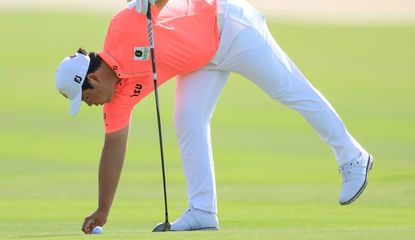 Tom Kim identifies his golf ball which is covered in mud