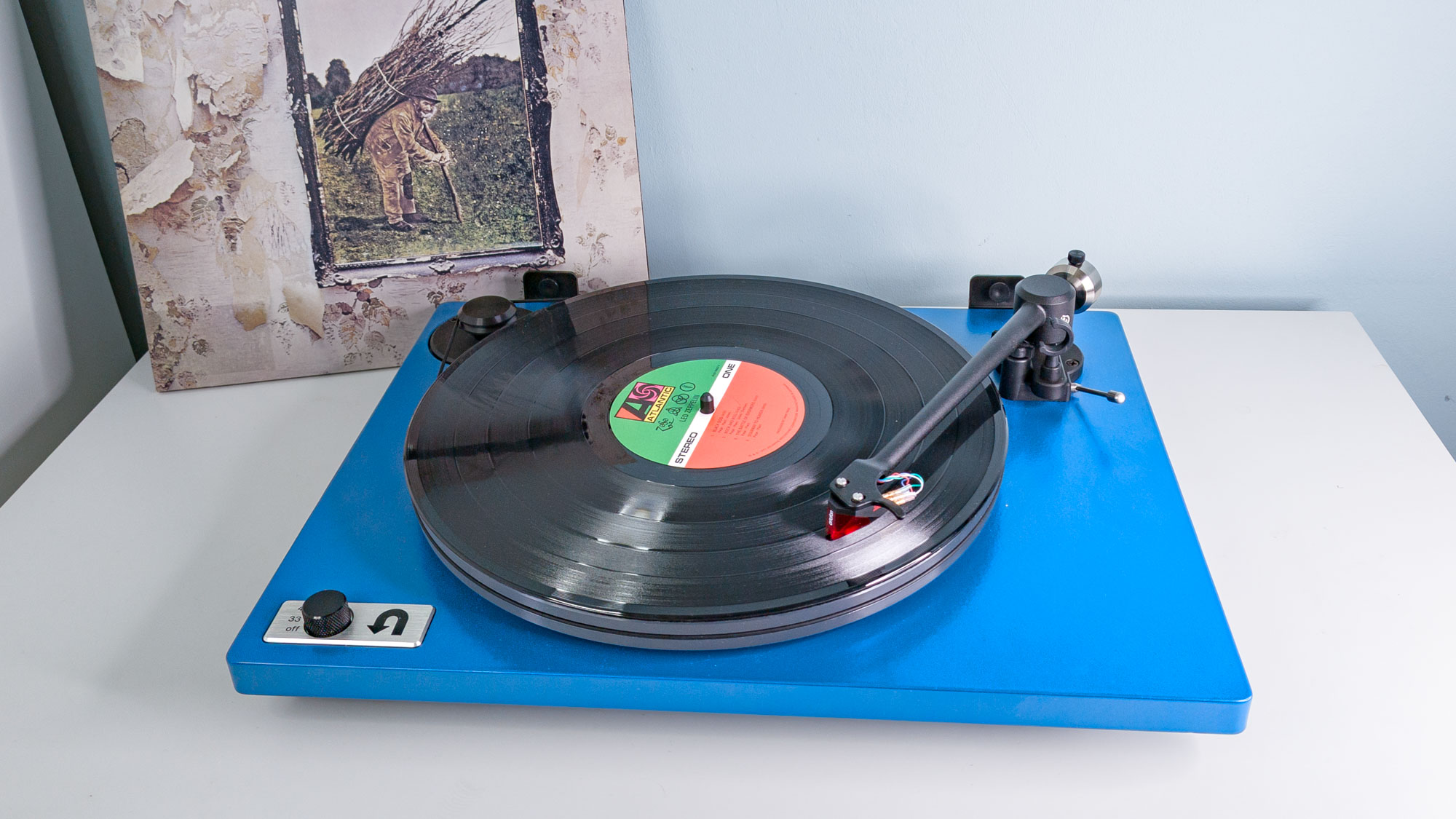 A Blue U-Turn Audio Orbit Special with a Led Zeppelin record on the platter, the cover behind the player leaning up against a light blue wall